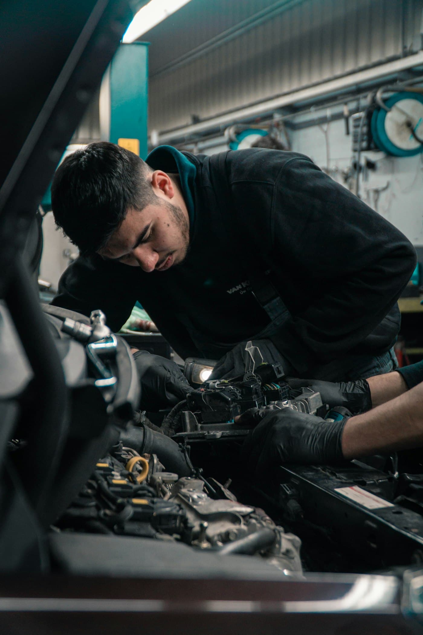 A technician leaning into an engine bay to work on ignition components