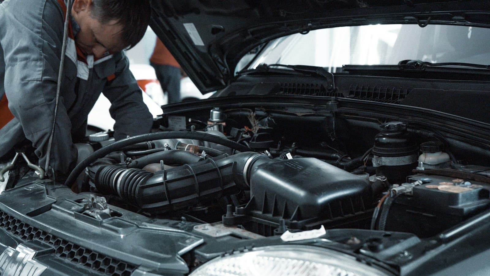 A technician leaning over an open hood to inspect the engine